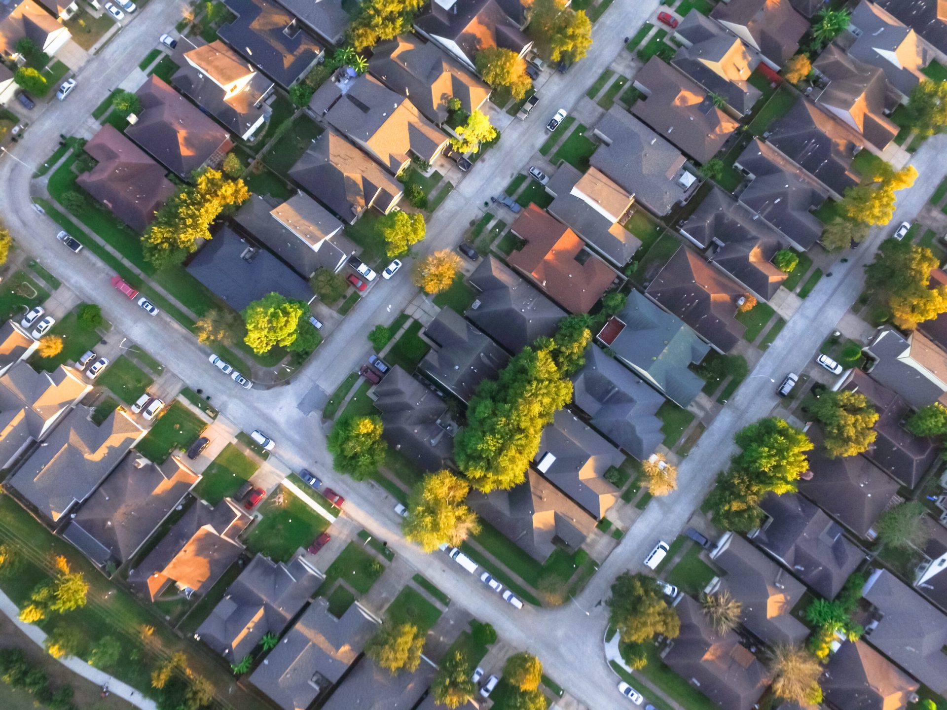 Aerial view of residential houses and driveways neighbourhood during a fall sunset.