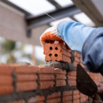 close up of bricklayer worker installing brick masonry on exteri