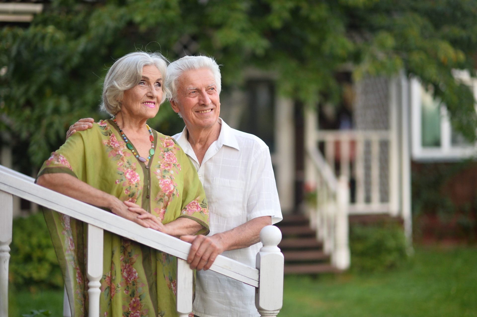 A retired couple standing outside their new house