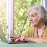 beautiful elderly woman uses her laptop at her country house